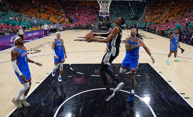 San Antonio Spurs forward Victor Wembanyama, middle, goes to the basket during the second half of Game 3 in the Western Conference finals NBA basketball playoffs series against the Oklahoma City Thunder Friday, May 22, 2026, in San Antonio. (AP Photo/Darren Abate)