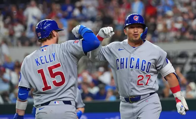 Chicago Cubs' Seiya Suzuki (27) is greeted by Carson Kelly (15) near home plate after hitting a two-run home run off Texas Rangers starting pitcher Kumar Rocker during the fourth inning of a baseball game Friday, May 8, 2026, in Arlington, Texas. (AP Photo/Julio Cortez)