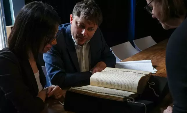 From left, Elisabetta Magnanti and Mark Faulkner from Dublin's Trinity College and Valentina Longo of Rome's National Central Library look at a manuscript containing a rare, long-lost copy of Caedmon's Hymn, the first poem ever to be written down in Old English, at Rome's National Library, Thursday, May 8, 2026. (AP Photo/Andrea Rosa)