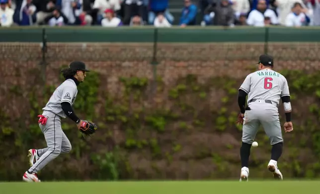 Arizona Diamondbacks center fielder Alek Thomas , left, and second baseman Ildemaro Vargas (6) chase a hit from Chicago Cubs' Carson Kelly (15) during the first inning of a baseball game Friday, May 1, 2026, in Chicago. (AP Photo/Erin Hooley)