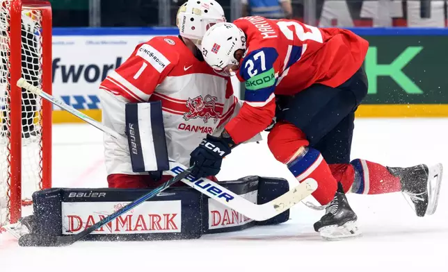 Denmark's goaltender Nicolaj Henriksen, left, vies for the puck against Norway's Andreas Martinsen, right, during the 2026 IIHF Men's Ice Hockey World Championship preliminary round group B game between Norway and Denmark, in Fribourg, Switzerland, Tuesday, May 26, 2026. (Laurent Gillieron/Keystone via AP)