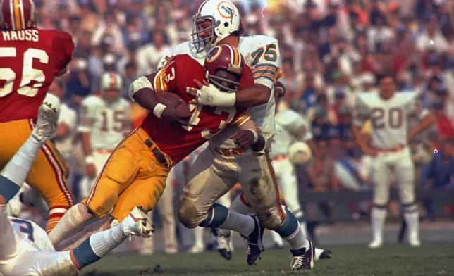 Washington Redskins running back Larry Brown (43) is stopped in his tracks by Miami Dolphins defender Manny Fernandez (75) during the NFL football Super Bowl VII game in Los Angeles, Jan. 14, 1973. (AP Photo/File)