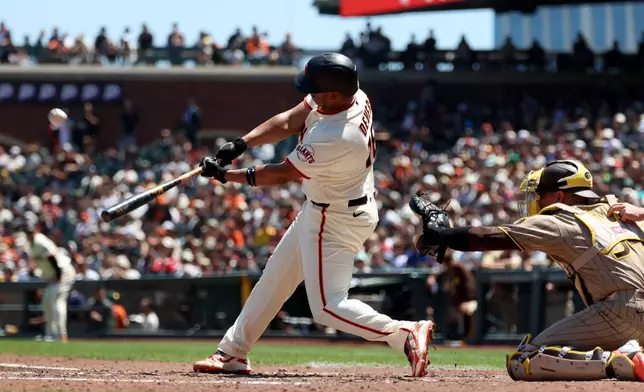 San Francisco Giants' Rafael Devers, left, hits a home run in front of San Diego Padres catcher Freddy Fermin during the fifth inning of a baseball game in San Francisco, Wednesday, May 6, 2026. (AP Photo/Jed Jacobsohn)