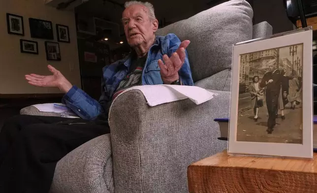 Freeman K. Johnson, a 106-year-old Pearl Harbor survivor, gestures during an interview, next to a photograph of himself on leave in 1943, at his home on May 6, 2026, in Centerville, Mass. (AP Photo/Charles Krupa)