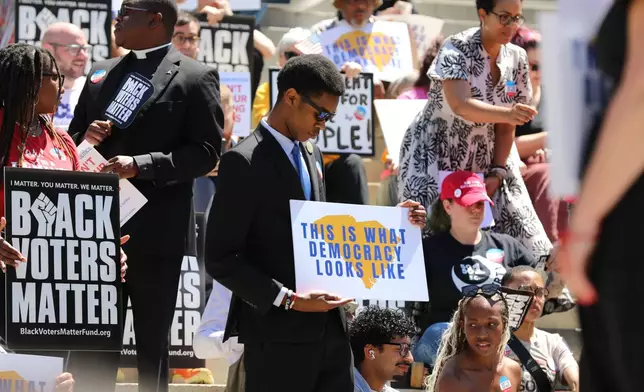 A protestor stands outside the South Carolina Statehouse on Thursday, May 14, 2026, in Columbia, S.C. (AP Photo/Jeffrey Collins)