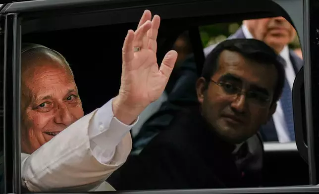 Pope Leo XIV waves from his car as he leaves with his personal secretary, Monsignor Edgard Iván Rimaycuna Inga, right, after visiting the Città Universitaria (University City) at Sapienza University of Rome where he met with faculty and students at the institution's primary campus, one of the world's oldest and largest universities, Thursday, May 14, 2026. (AP Photo/Gregorio Borgia)
