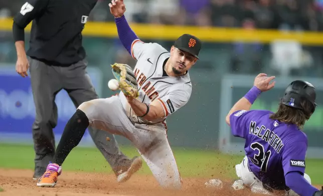 San Francisco Giants shortstop Willy Adames, front left, fields a throw as Colorado Rockies' Jake McCarthy, right, steals second base in the seventh inning of a baseball game Saturday, May 30, 2026, in Denver. (AP Photo/David Zalubowski)