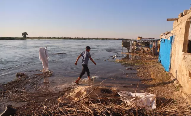 A boy walks through floodwaters along the banks of the Euphrates River near Raqqa, northeastern Syria, Tuesday, May 26, 2026. (AP Photo/Baderkhan Ahmad)