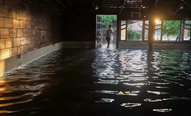 A man walks through a flooded restaurant along the banks of the Euphrates River near Raqqa, northeastern Syria, Tuesday, May 26, 2026. (AP Photo/Baderkhan Ahmad)