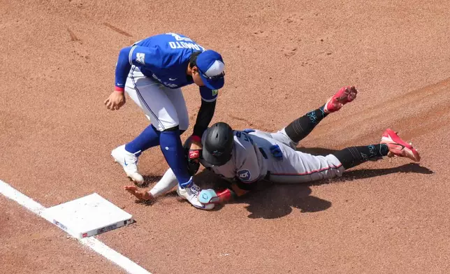 Miami Marlins' Heriberto Hernández (13) is caught trying to steal third by Toronto Blue Jays third baseman Kazuma Okamoto (7) during the sixth inning of a baseball game in Toronto, Wednesday, May 27, 2026. (Chris Young/The Canadian Press via AP)