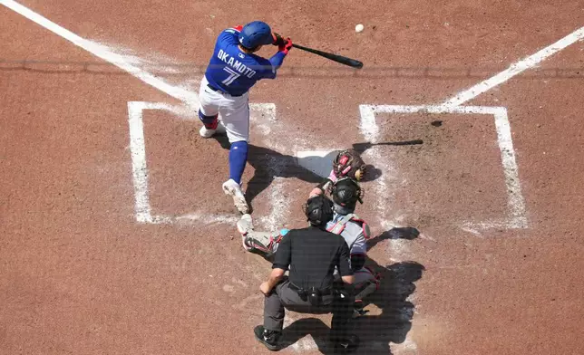 Toronto Blue Jays' Kazuma Okamoto (7) hits a solo home run in front of Miami Marlins catcher Liam Hicks (34) during the sixth inning of a baseball game in Toronto, Wednesday, May 27, 2026. (Chris Young/The Canadian Press via AP)