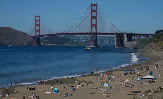 FILE - The Golden Gate Bridge is seen behind people visiting Baker Beach in San Francisco on March 18, 2026. (AP Photo/Jeff Chiu, File)
