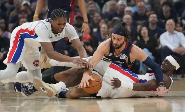 Detroit Pistons' Ausar Thompson, left, and Cleveland Cavalirs' Max Strus, center, reach for the ball over Caris LeVert, right, in the first half of Game 6 of a second-round NBA basketball playoffs series Friday, May 15, 2026, in Cleveland. (AP Photo/Sue Ogrocki)