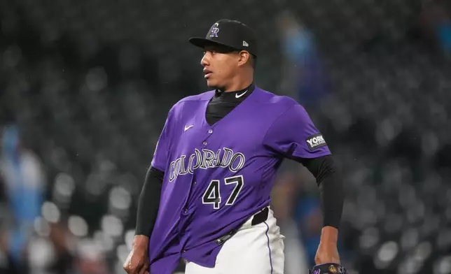 Colorado Rockies relief pitcher Juan Mejia pulls out his shirt after retiring Texas Rangers' Danny Jansen for the final out in a baseball game Monday, May 18, 2026, in Denver. (AP Photo/David Zalubowski)