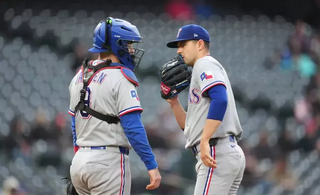 Texas Rangers catcher Danny Jansen, left, confers with starting pitcher MacKenzie Gore, right, after Gore loaded the bases in the first inning of a baseball game against the Colorado Rockies, Monday, May 18, 2026, in Denver. (AP Photo/David Zalubowski)