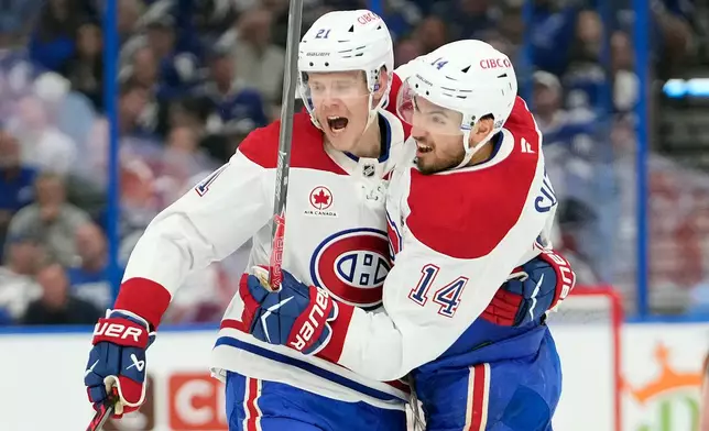 Montréal Canadiens center Nick Suzuki (14) celebrates his goal against the Tampa Bay Lightning with defenseman Kaiden Guhle (21) during the first period in Game 7 of an NHL hockey Stanley Cup first-round playoff series, Sunday, May 3, 2026, in Tampa, Fla. (AP Photo/Chris O'Meara)