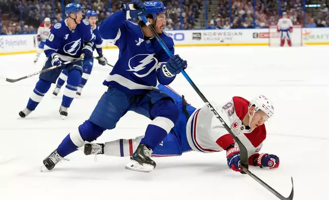 Tampa Bay Lightning defenseman Charle-Edouard D'Astous (51) knocks down Montréal Canadiens right wing Ivan Demidov (93) during the first period in Game 7 of an NHL hockey Stanley Cup first-round playoff series, Sunday, May 3, 2026, in Tampa, Fla. (AP Photo/Chris O'Meara)