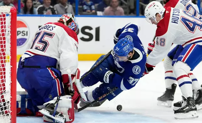Montréal Canadiens defenseman Lane Hutson (48) takes down Tampa Bay Lightning center Yanni Gourde (37) in front of goaltender Jakub Dobes (75) during the second period in Game 7 of an NHL hockey Stanley Cup first-round playoff series, Sunday, May 3, 2026, in Tampa, Fla. (AP Photo/Chris O'Meara)