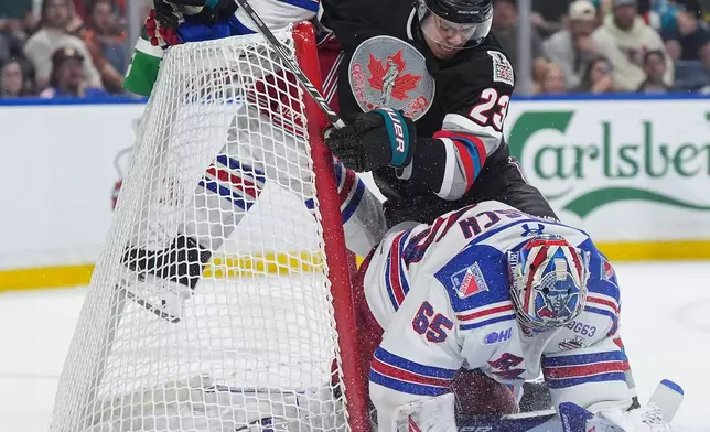 Kelowna Rockets' Hayden Paupanekis (23) and Kitchener Rangers' Andrew MacNiel (43) crash into the net as Rangers goalie Christian Kirsch (65) makes a save during the second period of a Memorial Cup hockey game in Kelowna, British Columbia, Friday, May 22, 2026. (Darryl Dyck/The Canadian Press via AP)