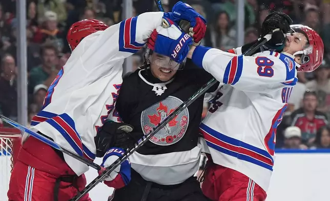 Kelowna Rockets' Hayden Paupanekis, centre, gets into a scuffle with Kitchener Rangers' Alexander Bilecki, right, and Andrew MacNiel during the second period of a Memorial Cup hockey game in Kelowna, British Columbia, Friday, May 22, 2026. (Darryl Dyck/The Canadian Press via AP)