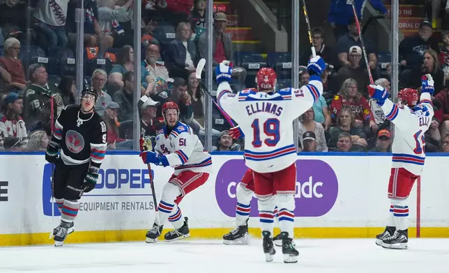 Kitchener Rangers' Jared Woolley (51), Luke Ellinas (19) and Haeden Ellis (13) celebrate Woolley's goal as Kelowna Rockets' Shane Smith (9) skates past during the second period of a Memorial Cup hockey game in Kelowna, British Columbia, Friday, May 22, 2026. (Darryl Dyck/The Canadian Press via AP)