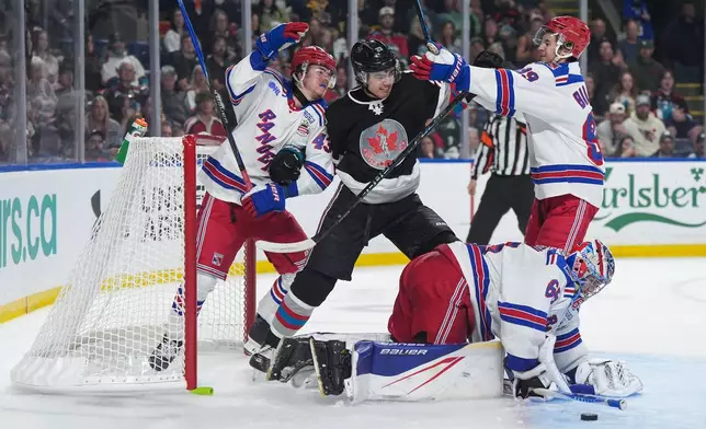 Kitchener Rangers' Andrew MacNiel (43) and Alexander Bilecki (89) go after Kelowna Rockets' Hayden Paupanekis (23) after he and MacNiel crashed into the net behind Rangers goalie Christian Kirsch, bottom, during the second period of a Memorial Cup hockey game in Kelowna, British Columbia, Friday, May 22, 2026. (Darryl Dyck/The Canadian Press via AP)