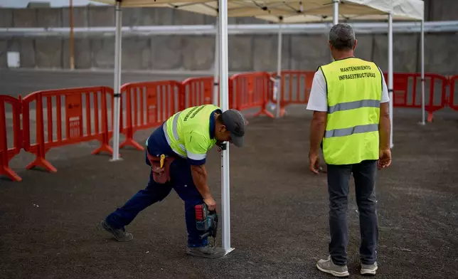 Workers set up temporary shelters in the area where passengers from the MV Hondius cruise ship are expected to arrive at the port of Granadilla in Tenerife, Canary Islands, Spain, Saturday, May 9, 2026. (AP Photo/Manu Fernandez)