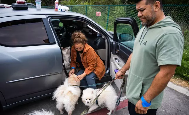 People tend to their pets outside Freedom Hall, an evacuation center in Fountain Valley, Calif., on Monday, May 25, 2026. (AP Photo/Ethan Swope)