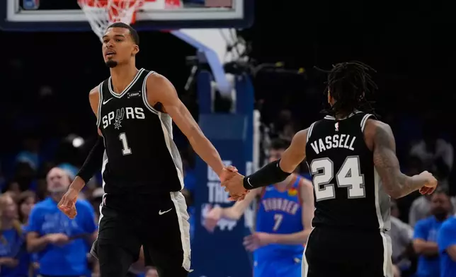 San Antonio Spurs forward Victor Wembanyama (1) celebrates with guard Devin Vassell (24) during the second overtime of Game 1 in a third-round NBA basketball playoffs series against the Oklahoma City Thunder Monday, May 18, 2026, in Oklahoma City. (AP Photo/Tony Gutierrez)