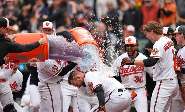 Baltimore Orioles' Colton Cowser, center front, celebrates with teammates after hitting a walkoff three-run home run during the ninth inning in the first baseball game of a doubleheader against the Detroit Tigers, Sunday, May 24, 2026, in Baltimore. (AP Photo/Stephanie Scarbrough)