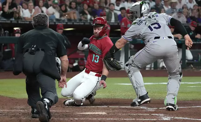 Colorado Rockies catcher Hunter Goodman tags out Arizona Diamondbacks' Tim Tawa (13) trying to score on a ball hit by Ketel Marte in the sixth inning of a baseball game, Saturday, May 23, 2026, in Phoenix. (AP Photo/Rick Scuteri)