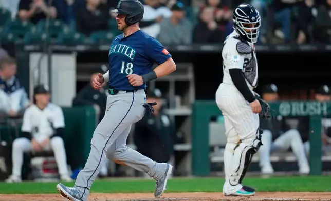 Seattle Mariners' Mitch Garver (18) jogs by Chicago White Sox catcher Edgar Quero, right, to score on a sacrifice fly hit by Rob Refsnyder during the fifth inning of a baseball game Saturday, May 9, 2026, in Chicago. (AP Photo/Erin Hooley)