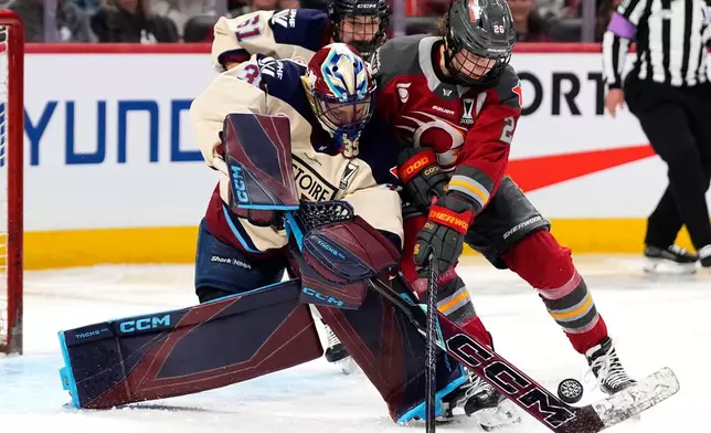 Montreal Victoire goaltender Ann-Renee Desbiens, front left, comes out of her crease to challenge Ottawa Charge's Emily Clark (26) for the puck during the second period of Game 3 in the PWHL Walter Cup finals hockey series in Ottawa, Ontario, Monday May 18, 2026. (Justin Tang/The Canadian Press via AP)