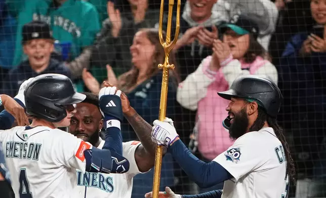 Seattle Mariners' J.P. Crawford, right, hands the trident to Colt Emerson (4) after Emerson hit a three-run home run against the Chicago White Sox, his first major league hit, during the eighth inning of a baseball game, Monday, May 18, 2026, in Seattle. (AP Photo/Lindsey Wasson)