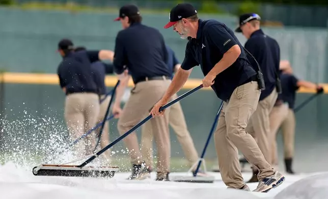 Atlanta Braves grounds crew take water off the tarp covering the field in the sixth inning of a baseball game in rain delay between the Atlanta Braves and the Washington Nationals, Sunday, May 24, 2026, in Atlanta. (AP Photo/Mike Stewart)