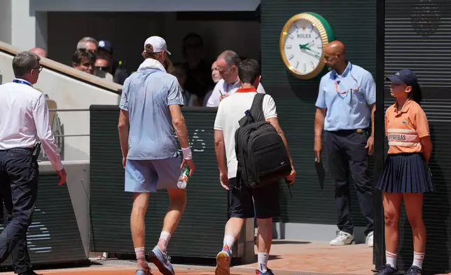 Jannik Sinner of Italy, centre left, leaves the court for medical check during the second round men's singles tennis match against Juan Manuel Cerundolo of Argentina at the French Open tennis tournament in Paris, Thursday, May 28, 2026. (AP Photo/Thibault Camus)