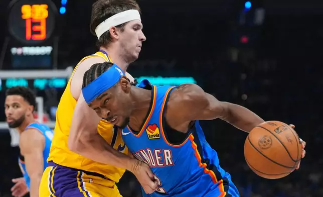 Oklahoma City Thunder guard Shai Gilgeous-Alexander, right, drives to the basket as Los Angeles Lakers guard Austin Reaves, left, defends second half of Game 1 in a second-round NBA basketball playoffs series Tuesday, May 5, 2026 in Oklahoma City. (AP Photo/Kyle Phillips)