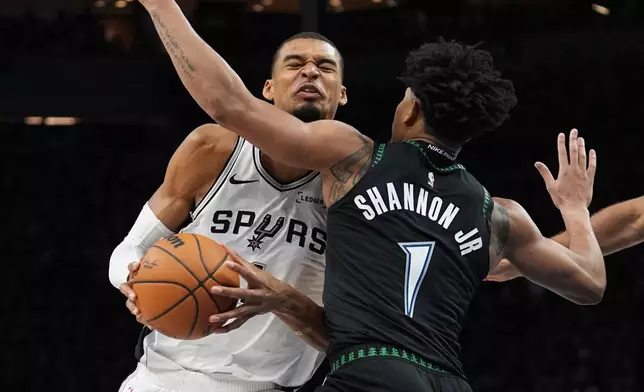 San Antonio Spurs forward Victor Wembanyama, left, is fouled by Minnesota Timberwolves guard Terrence Shannon Jr. (1) as he drives to the basket during the second half of Game 3 of a NBA basketball second-round playoff series in Minneapolis, Friday, May 8, 2026. (AP Photo/Abbie Parr)