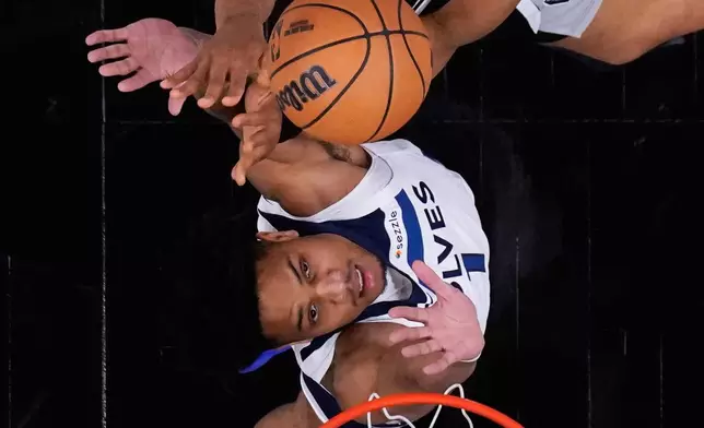 San Antonio Spurs forward Keldon Johnson, top, drives to the basket against Minnesota Timberwolves guard Terrence Shannon Jr. (1) during the first half of Game 5 of an NBA basketball second-round playoffs series in Minneapolis, Tuesday, May 12, 2026. (AP Photo/Eric Gay)