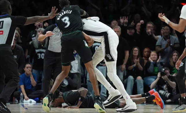 Minnesota Timberwolves center Naz Reid (11) falls to the court after he was fouled by San Antonio Spurs forward Victor Wembanyama (1) as he and forward Jaden McDaniels (3) battled for a rebound during the first half of Game 4 of an NBA basketball second-round playoffs series in Minneapolis, Sunday, May 10, 2026. (AP Photo/Abbie Parr)