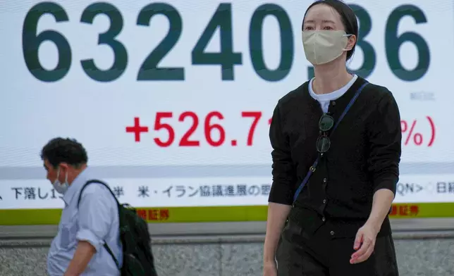 People walk in front of an electronic stock board showing Japan's Nikkei index at a securities firm Monday, May 11, 2026, in Tokyo. (AP Photo/Eugene Hoshiko)