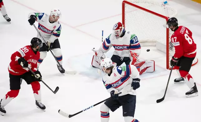 Canada's Ryan O'Reilly, left, scores the 4-4 against Norway's goaltender Tobias Normann, top center, Norway's Christian Kaasastul, top left, Norway's Max Krogdahl, bottom center, next to Canada's Sidney Crosby, right, during the 2026 IIHF Men's Ice Hockey World Championship preliminary round group B game between Canada and Norway, in Fribourg, Switzerland, Thursday, May 21, 2026. (Anthony Anex/Keystone via AP)
