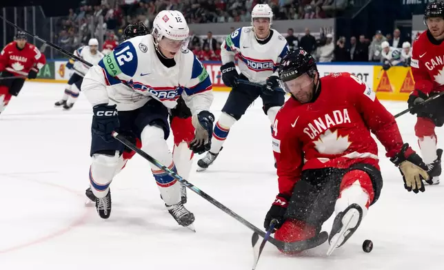 Norway's Noah Steen, left, and Canada's Morgan Rielly fight for the puck during the 2026 IIHF Men's Ice Hockey World Championship preliminary round group B game between Canada and Norway, in Fribourg, Switzerland, Thursday, May 21, 2026. (Anthony Anex/Keystone via AP)