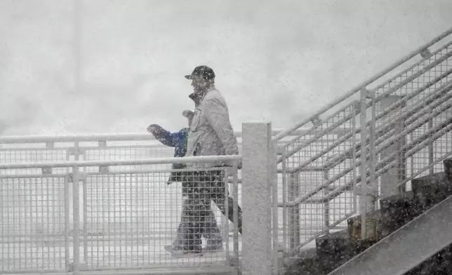 Hockey fans head into Ball Arena as a spring snow storm sweeps over the intermountain West before the first period of Game 2 of an NHL hockey Stanley Cup second-round playoff series between the Colorado Avalanche and Minnesota Wild Tuesday, May 5, 2026, in Denver. (AP Photo/David Zalubowski)