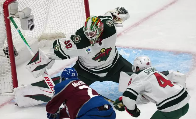 Colorado Avalanche center Nathan MacKinnon, front left, drives past Minnesota Wild defenseman Jared Spurgeon, right, to put a shot on goaltender Jesper Wallstedt in the first period of Game 1 of an NHL hockey Stanley Cup second-round playoff series, Sunday, May 3, 2026, in Denver. (AP Photo/David Zalubowski)