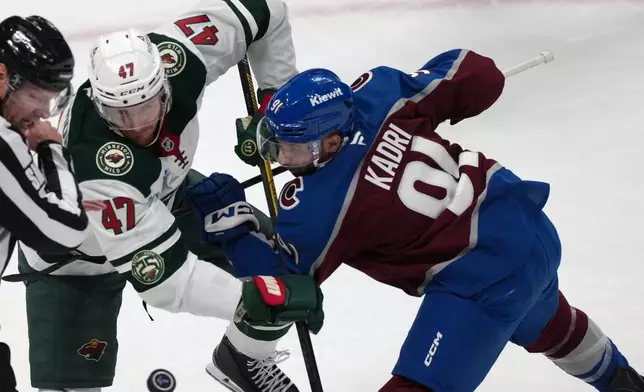 Minnesota Wild center Michael McCarron, left, fights for control of the puck with Colorado Avalanche center Nazem Kadri in the first period of Game 1 of an NHL hockey Stanley Cup second-round playoff series, Sunday, May 3, 2026, in Denver. (AP Photo/David Zalubowski)