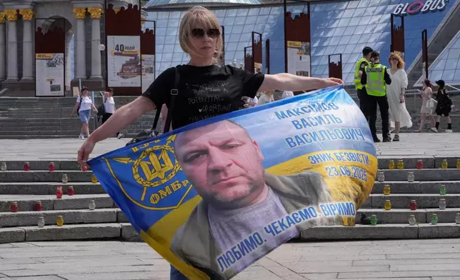 A woman holds a banner with the portrait of her relative during a rally of families of missing soldiers in Kyiv, Ukraine, Friday, May 22, 2026. (AP Photo/Efrem Lukatsky)