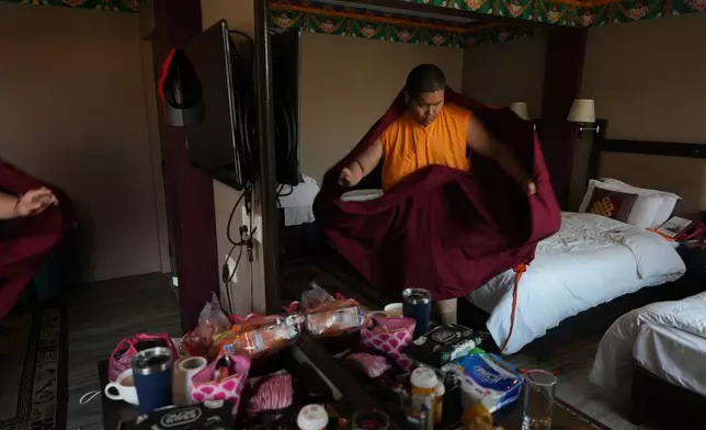 U.S.-born Buddhist lama Jalue Dorje puts on his monastic robes at his hotel room to start his day before attending a series of rituals and prayers at Shechen Monastery in Kathmandu, Nepal, on Saturday, April 11, 2026. (AP Photo/Luis Andres Henao)