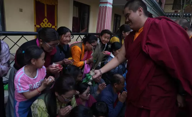 U.S.-born Buddhist lama Jalue Dorje smiles as he blesses people by tapping bowed heads with a ritual vase and a peacock feather at the end of 12 days of empowerments, or initiation rituals and teachings, bestowed by the abbot of Shechen Monastery in Kathmandu, Nepal, on Sunday, April 12, 2026. (AP Photo/Luis Andres Henao)