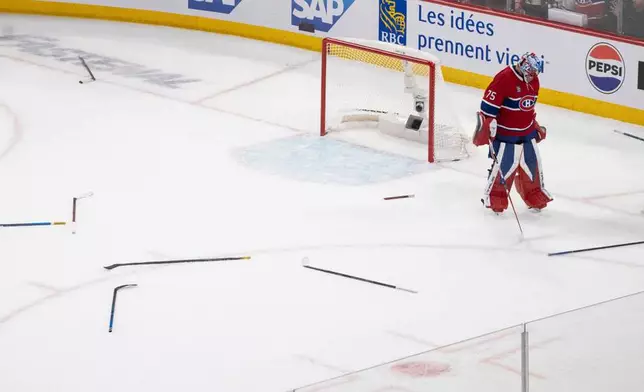 Montreal Canadiens goaltender Jakub Dobes (75) looks at hockey sticks left over from a fight between multiple players from both teams during the third period of Game 3 in a second-round NHL hockey Stanley Cup playoff series in Montreal, Sunday, May 10, 2026. (Christinne Muschi/The Canadian Press via AP)